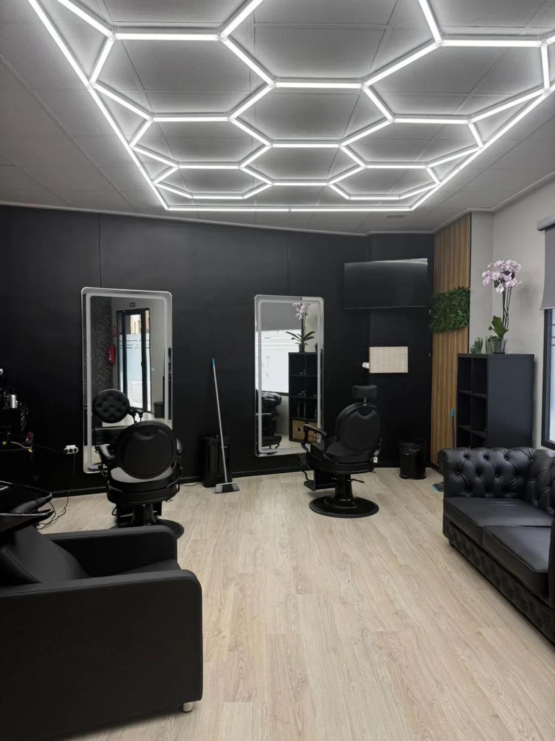 Interior de la barbería: dos puestos de corte con espejos e iluminación hexagonal